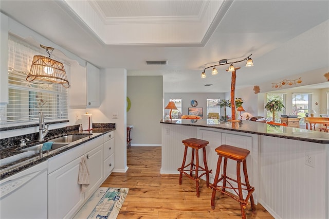 7216 11th Ave W Unit 203, Bradenton, FL 34209 - kitchen featuring white dishwasher, a breakfast bar area, white cabinets, light wood finished floors, and a raised ceiling
