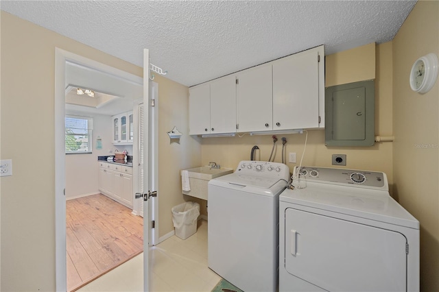 7216 11th Ave W Unit 203, Bradenton, FL 34209 - washroom featuring cabinet space, electric panel, independent washer and dryer, a textured ceiling, and light wood-style floors