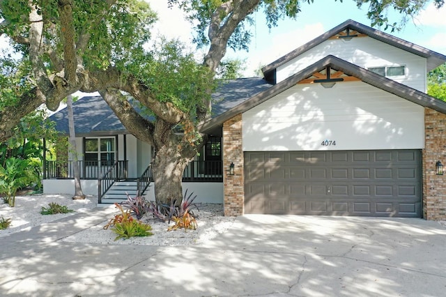 4074 Redbird Cir, Sarasota, FL 34231 - view of front of home with brick siding, a porch, driveway, and a garage