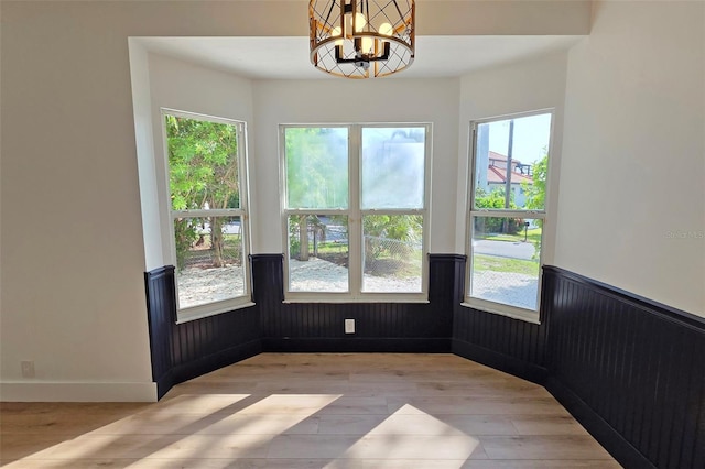 4074 Redbird Cir, Sarasota, FL 34231 - unfurnished room featuring light wood-style floors, a wainscoted wall, healthy amount of natural light, and a chandelier