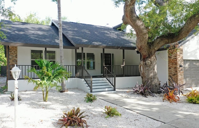4074 Redbird Cir, Sarasota, FL 34231 - view of front facade with covered porch, a shingled roof, and stucco siding