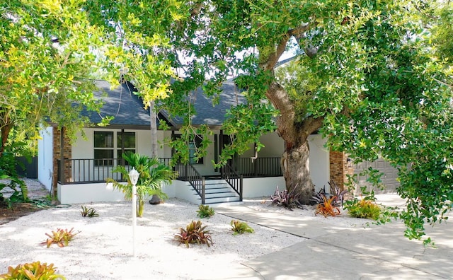 4074 Redbird Cir, Sarasota, FL 34231 - view of front facade featuring covered porch, roof with shingles, and stucco siding