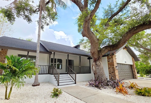 4074 Redbird Cir, Sarasota, FL 34231 - view of front facade with a garage, covered porch, roof with shingles, stucco siding, and driveway