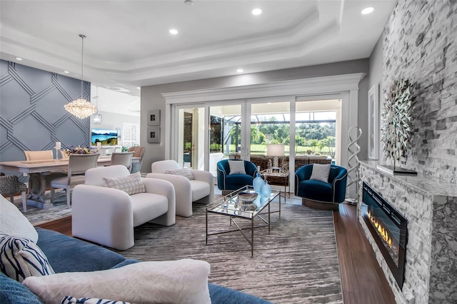 462 E Macewen Dr, Osprey, FL 34229 - living room with dark wood-style flooring, a stone fireplace, a raised ceiling, recessed lighting, and a chandelier