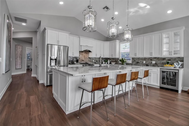 462 E Macewen Dr, Osprey, FL 34229 - kitchen with wine cooler, stainless steel fridge, vaulted ceiling, white cabinetry, and a kitchen island with sink