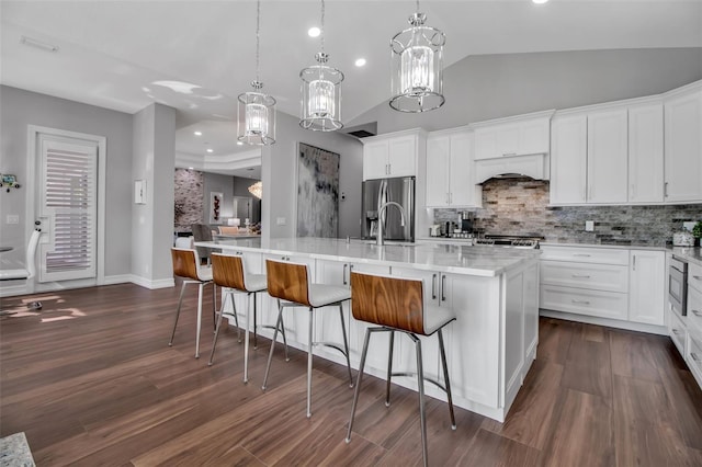 462 E Macewen Dr, Osprey, FL 34229 - kitchen featuring decorative backsplash, dark wood-type flooring, white cabinets, a kitchen island with sink, and lofted ceiling