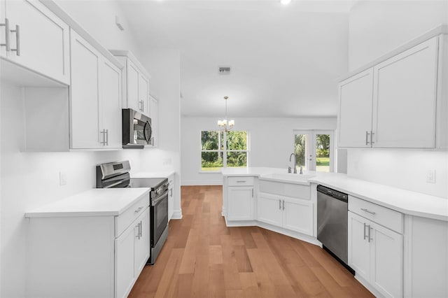 27471 Deep Creek Blvd, Punta Gorda, FL 33983 - kitchen featuring appliances with stainless steel finishes, a peninsula, white cabinetry, light countertops, and light wood-style flooring