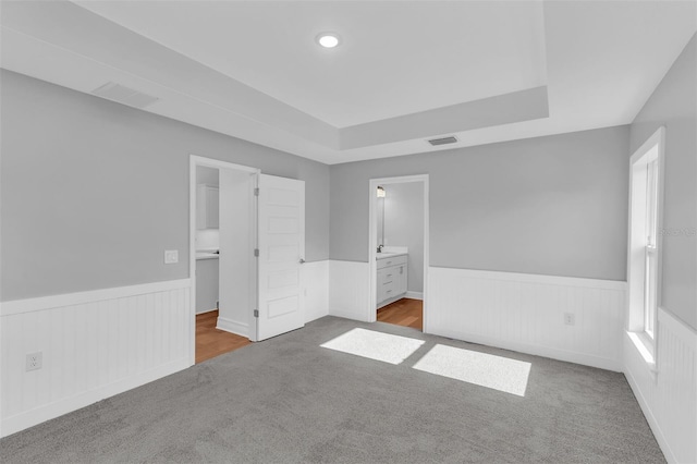 27471 Deep Creek Blvd, Punta Gorda, FL 33983 - unfurnished bedroom with wainscoting, carpet, a raised ceiling, connected bathroom, and a spacious closet