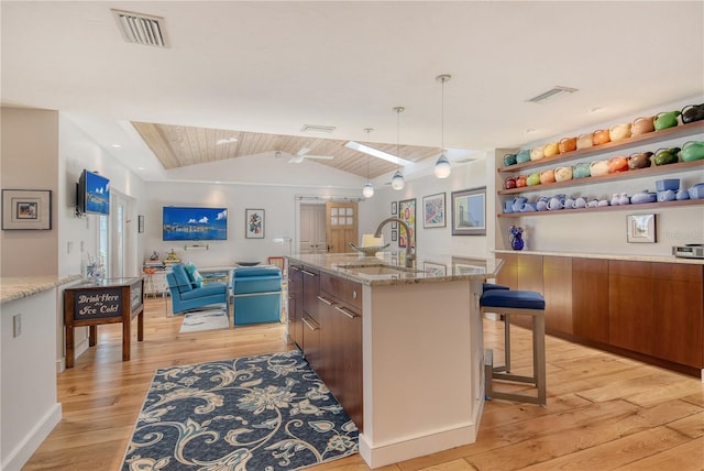 6308 4th Ave NW, Bradenton, FL 34209 - kitchen featuring light wood-type flooring, lofted ceiling, open floor plan, a breakfast bar, and open shelves