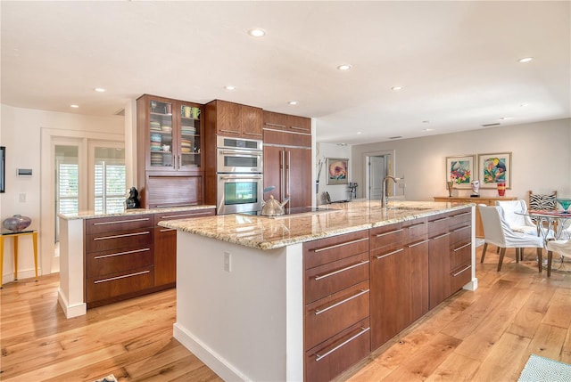 6308 4th Ave NW, Bradenton, FL 34209 - kitchen featuring stainless steel double oven, a kitchen island with sink, light wood-type flooring, recessed lighting, and stovetop