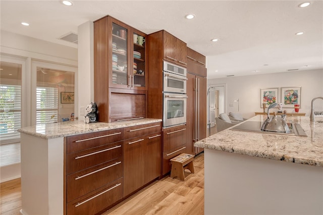 6308 4th Ave NW, Bradenton, FL 34209 - kitchen featuring light wood-type flooring, recessed lighting, glass insert cabinets, modern cabinets, and light stone counters
