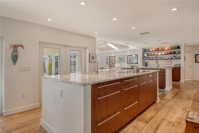 6308 4th Ave NW, Bradenton, FL 34209 - kitchen featuring a large island with sink, open shelves, modern cabinets, light wood-style flooring, and black electric cooktop