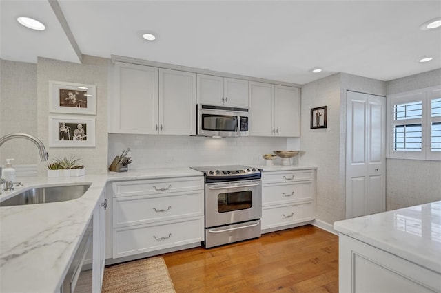 6480 Midnight Pass Rd Unit 211, Sarasota, FL 34242 - kitchen featuring appliances with stainless steel finishes, light wood-style flooring, light stone counters, tasteful backsplash, and recessed lighting