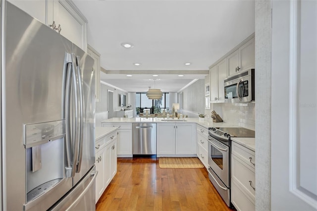 6480 Midnight Pass Rd Unit 211, Sarasota, FL 34242 - kitchen featuring appliances with stainless steel finishes, light countertops, light wood-style flooring, a peninsula, and white cabinets