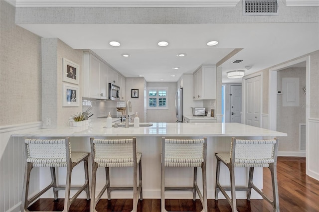 6480 Midnight Pass Rd Unit 211, Sarasota, FL 34242 - kitchen featuring dark wood-style flooring, a peninsula, light countertops, white cabinets, and crown molding