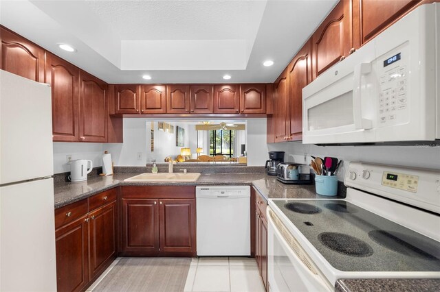 4415 45th Ave W Unit 102, Bradenton, FL 34210 - kitchen with white appliances, recessed lighting, dark countertops, a tray ceiling, and light tile patterned floors