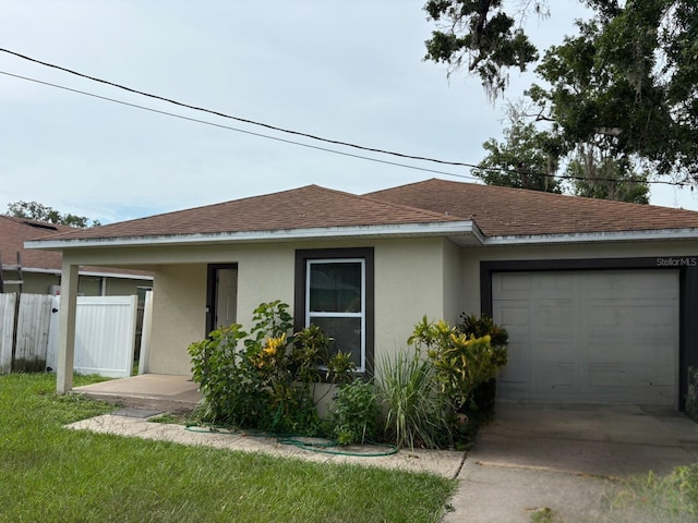 712 W Myrtle St, Lakeland, FL 33815 - view of front facade featuring stucco siding, roof with shingles, an attached garage, and concrete driveway