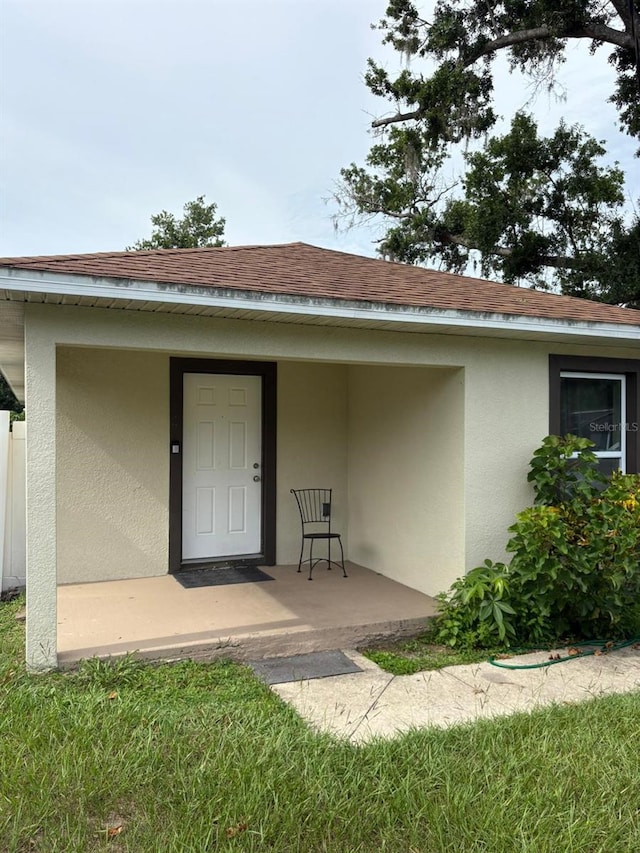 712 W Myrtle St, Lakeland, FL 33815 - view of exterior entry with stucco siding, covered porch, and a shingled roof