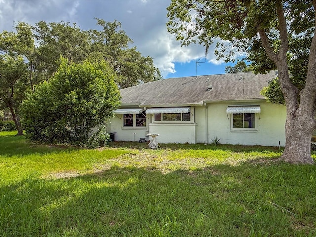 8606 Gold Pine Dr, Port Richey, FL 34668 - back of property featuring stucco siding, a lawn, and a shingled roof