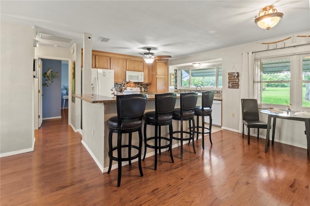 8606 Gold Pine Dr, Port Richey, FL 34668 - kitchen featuring white appliances, wood finished floors, tasteful backsplash, and a breakfast bar