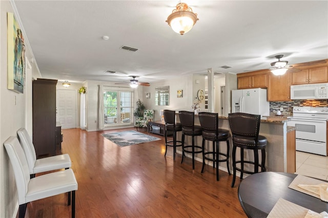 8606 Gold Pine Dr, Port Richey, FL 34668 - kitchen with white appliances, a ceiling fan, a breakfast bar, open floor plan, and tasteful backsplash