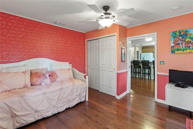 8606 Gold Pine Dr, Port Richey, FL 34668 - bedroom featuring wood finished floors, ornamental molding, white refrigerator with ice dispenser, ceiling fan, and a closet