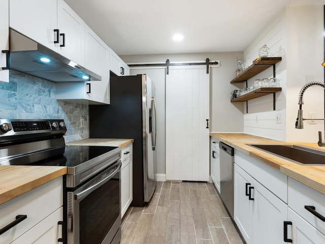 7424 Vista Way Unit 104, Bradenton, FL 34202 - kitchen with butcher block countertops, appliances with stainless steel finishes, under cabinet range hood, a barn door, and decorative backsplash