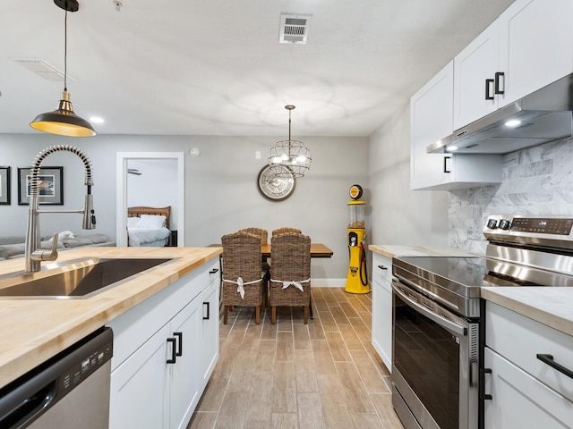 7424 Vista Way Unit 104, Bradenton, FL 34202 - kitchen with stainless steel appliances, wooden counters, under cabinet range hood, light wood-type flooring, and decorative light fixtures