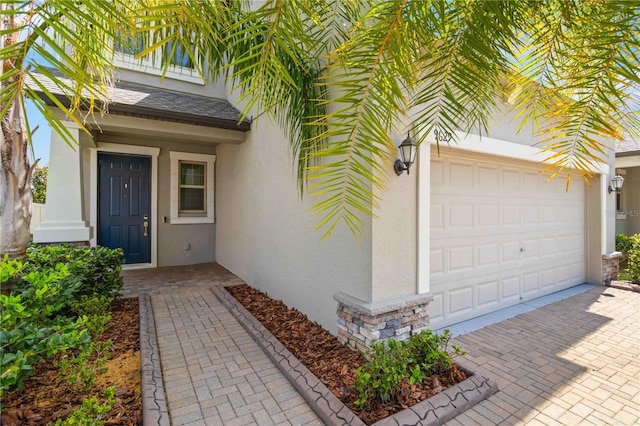 9629 Ivory Dr, Ruskin, FL 33573 - entrance to property with stucco siding, stone siding, decorative driveway, a garage, and roof with shingles