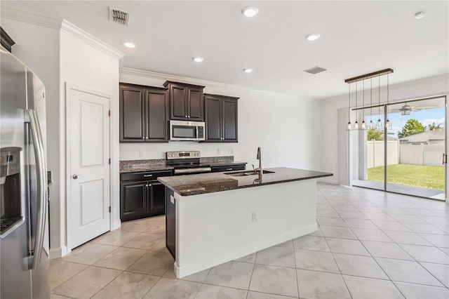 9629 Ivory Dr, Ruskin, FL 33573 - kitchen featuring appliances with stainless steel finishes, dark stone counters, a kitchen island with sink, light tile patterned floors, and recessed lighting