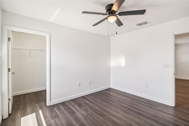 9629 Ivory Dr, Ruskin, FL 33573 - unfurnished bedroom featuring dark wood-style floors, a walk in closet, and a ceiling fan