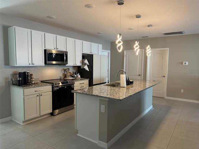 6 Pine Bluff Ln, Palm Coast, FL 32164 - kitchen featuring stainless steel appliances, a center island with sink, light tile patterned floors, light stone counters, and a textured ceiling