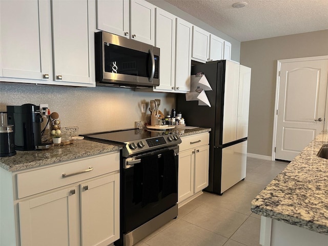 6 Pine Bluff Ln, Palm Coast, FL 32164 - kitchen with appliances with stainless steel finishes, light tile patterned floors, a textured ceiling, white cabinets, and light stone countertops