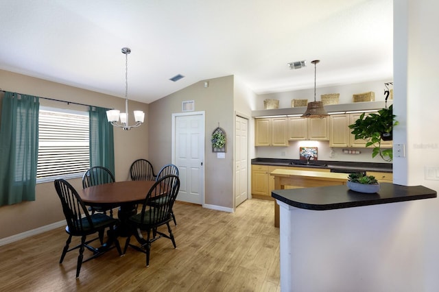 6115 68th Dr E, Palmetto, FL 34221 - kitchen featuring lofted ceiling, a chandelier, dark countertops, light wood-style floors, and hanging light fixtures