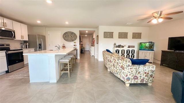 12293 Mountain Island Trl, Parrish, FL 34219 - kitchen with stainless steel appliances, open floor plan, white cabinets, a kitchen breakfast bar, and recessed lighting