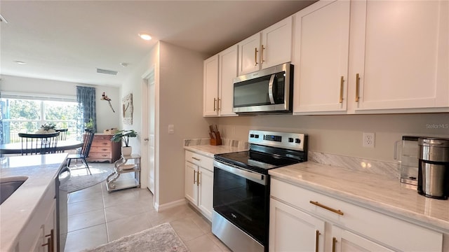 12293 Mountain Island Trl, Parrish, FL 34219 - kitchen with appliances with stainless steel finishes, white cabinets, light tile patterned floors, light stone countertops, and recessed lighting