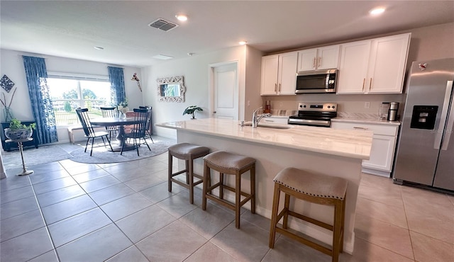 12293 Mountain Island Trl, Parrish, FL 34219 - kitchen featuring appliances with stainless steel finishes, white cabinets, a breakfast bar area, light tile patterned flooring, and recessed lighting