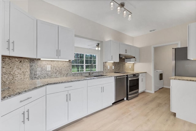 4050 Pinebrook Cir Unit 5, Bradenton, FL 34209 - kitchen with appliances with stainless steel finishes, under cabinet range hood, washer / clothes dryer, light stone countertops, and light wood-style floors