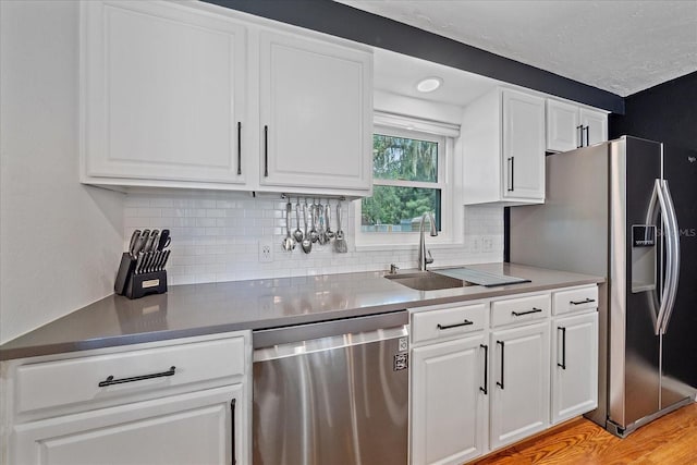 626 Hand Ave, Sarasota, FL 34232 - kitchen featuring stainless steel appliances, backsplash, white cabinets, and light wood-type flooring