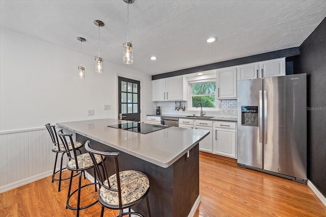626 Hand Ave, Sarasota, FL 34232 - kitchen with stainless steel appliances, light wood-type flooring, a kitchen bar, white cabinets, and a peninsula