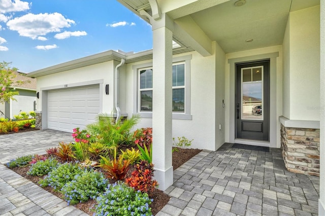5318 124th Ave E, Parrish, FL 34219 - doorway to property featuring an attached garage, stucco siding, decorative driveway, and stone siding