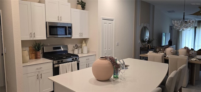 9084 Tequila Sunrise Dr, Sarasota, FL 34241 - kitchen featuring appliances with stainless steel finishes, a center island with sink, white cabinetry, a breakfast bar area, and light countertops