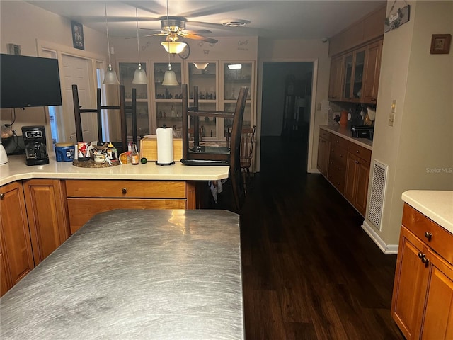 2065 Flamingo Dr, Bartow, FL 33830 - kitchen featuring brown cabinets, a ceiling fan, dark wood finished floors, glass insert cabinets, and a peninsula
