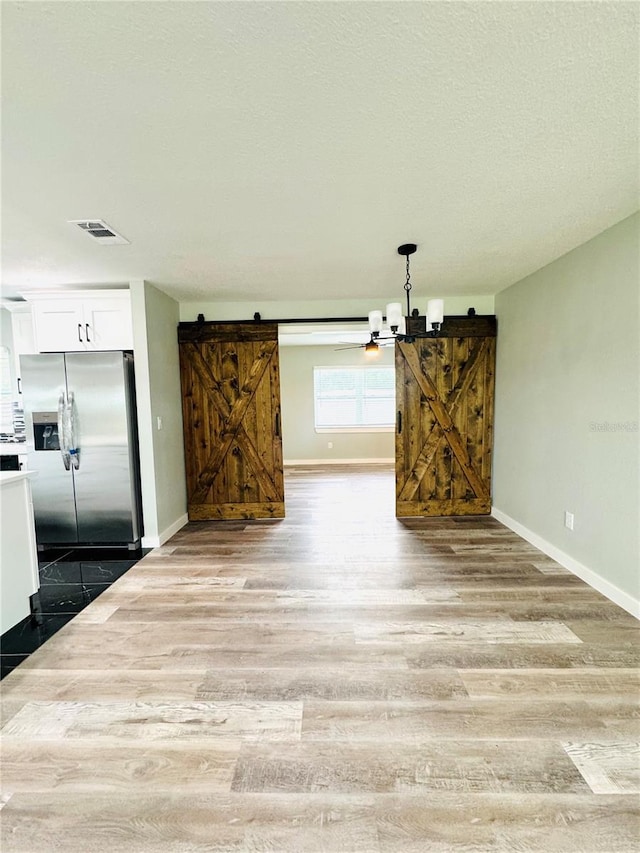 7013 Symmes Rd, Gibsonton, FL 33534 - unfurnished dining area featuring a barn door, wood finished floors, and a textured ceiling