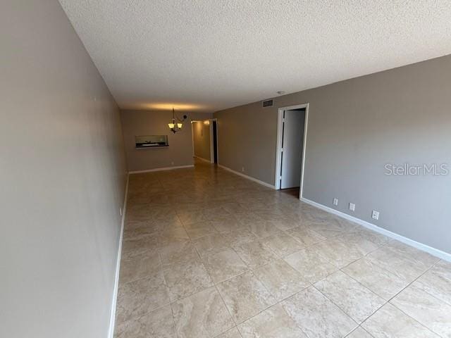 2763 Woodgate Ln Unit 111, Sarasota, FL 34231 - spare room featuring a textured ceiling and a chandelier