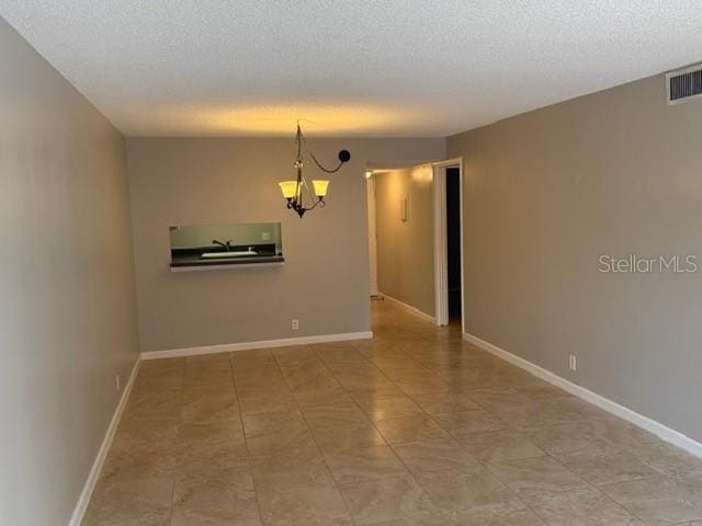 2763 Woodgate Ln Unit 111, Sarasota, FL 34231 - empty room featuring a chandelier and a textured ceiling