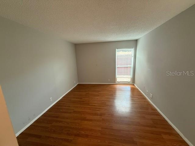 2763 Woodgate Ln Unit 111, Sarasota, FL 34231 - spare room featuring wood finished floors and a textured ceiling
