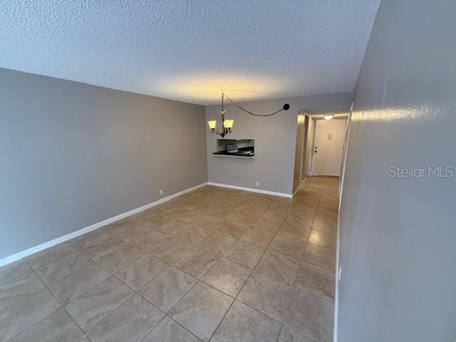 2763 Woodgate Ln Unit 111, Sarasota, FL 34231 - unfurnished room with a chandelier, a textured ceiling, and light tile patterned floors