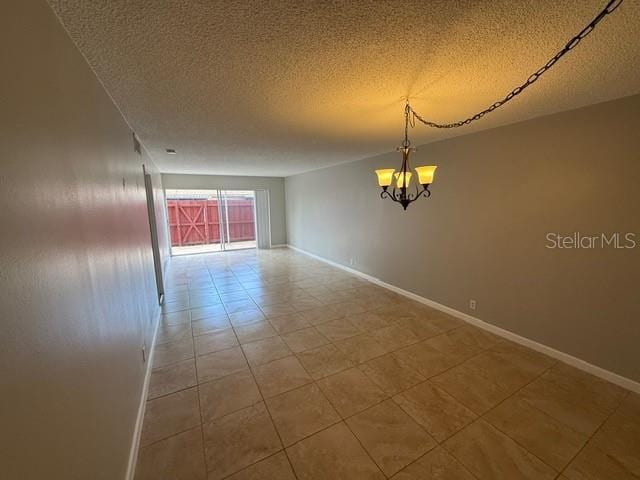 2763 Woodgate Ln Unit 111, Sarasota, FL 34231 - tiled empty room featuring a chandelier and a textured ceiling