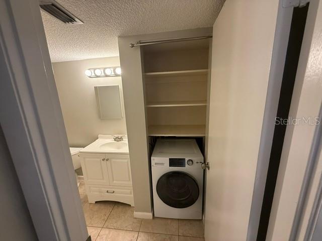 2763 Woodgate Ln Unit 111, Sarasota, FL 34231 - laundry room with washer / dryer, light tile patterned floors, and a textured ceiling